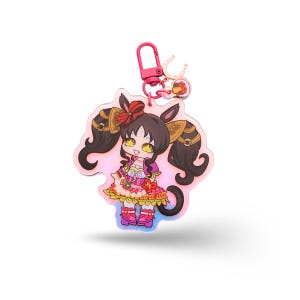 Op de afbeelding: Een kleurrijke anime-stijl sleutelhanger met een personage met donker haar in staartjes, gekleed in een roze en oranje jurk. De sleutelhanger heeft een roze sluiting en een kleine bedel. Het ontwerp staat op een heldere, iriserende achtergrond.