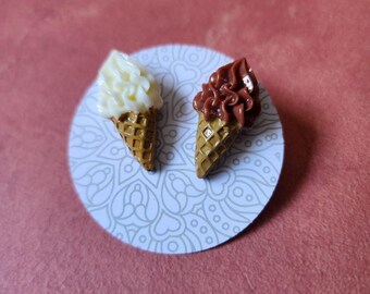 May include: A pair of ice cream cone earrings, one with white ice cream and one with brown ice cream.