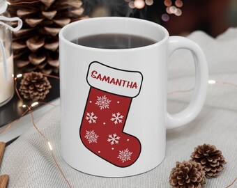 May include: White ceramic mug with a red and white Christmas stocking design. The stocking has snowflakes and the name "Samantha" on it.