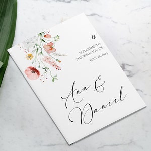 May include: A white wedding program with a floral design featuring pink, red, and yellow flowers. The text reads "Welcome to the Wedding of Ann & Daniel July 28, 2023".