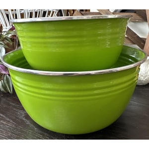 May include: Two nested, lime green metal mixing bowls with silver rims. The bowls have a ribbed design around the exterior. The larger bowl is at the bottom, with the smaller bowl nested inside.
