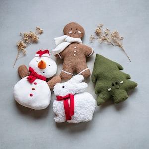 May include: A set of four plush toys: a gingerbread person, a snowman, a white bunny, and a green Christmas tree. The toys are all handmade and have embroidered faces.