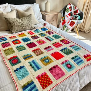 May include: A crocheted throw blanket with a patchwork design featuring various colors and textures. The blanket is made up of squares with different patterns, including stripes, polka dots, and floral motifs. The blanket is laid out on a bed with white bedding.