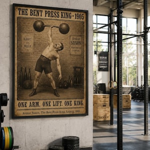 Può includere: Un poster incorniciato in stile vintage intitolato THE BENT PRESS KING 1905 con un'illustrazione color seppia di una persona che esegue un sollevamento con bilanciere a un braccio. Il testo recita KRAFT IST WILLE, Arthur Saxon e ONE ARM. ONE LIFT. ONE KING.