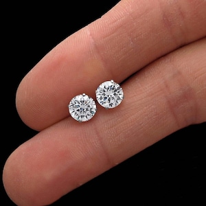 May include: A pair of silver stud earrings with clear round cubic zirconia stones.
