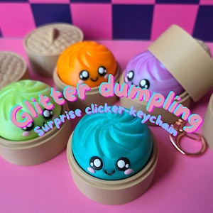 May include: A collection of colorful, glittery dumpling-shaped keychains in shades of green, orange, purple, and teal, each with a smiling face. The keychains are in small, brown steamer baskets, with the text "Glitter dumpling Surprise clicker-keychain".