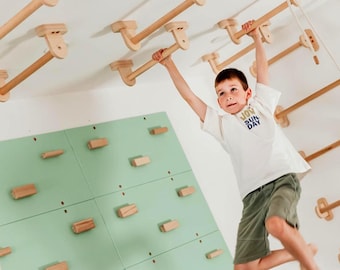 May include: A light green climbing wall with wooden blocks and a ceiling-mounted wooden monkey bar system. The wall features a grid of rectangular wooden holds, while the overhead structure consists of parallel wooden bars attached to the ceiling.