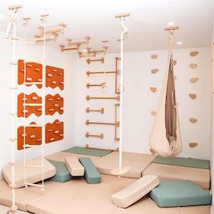Puede incluir: Un área de juegos interior para niños con una escalera de cuerda, un rocódromo, barras de madera y un columpio. La habitación está equipada con colchonetas acolchadas en tonos neutros. El diseño promueve el juego activo y el desarrollo físico.