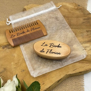 Könnte beinhalten: Ein Holz-Bartkamm- und -Bürsten-Set in einer weißen Organza-Tasche. Der Kamm und die Bürste sind beide mit dem Text "La Barbe de Florian" graviert.