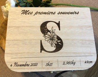 Puede incluir: Una caja de madera para recuerdos con un diseño floral y la letra "S" grabada en la tapa. La caja también incluye el texto "Mes premiers souvenirs", "4 Novembre 2021", "5h15", "2,960kg" y "49cm".