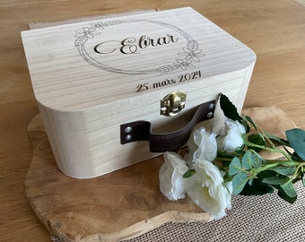 Puede incluir: Una caja de recuerdo de madera clara con una manija de cuero y un diseño floral grabado en la tapa. La tapa está grabada con el nombre "Ebrar" y la fecha "25 mars 2024".