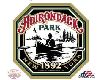 May include: Adirondack Park window decal featuring a vintage illustration of a canoe on a lake with a person paddling. The decal is green, gold, and black with the text "Adirondack Park" in red and "New 1892 York" in black. The decal also includes the text "Happy Travels!" and a logo for Mossback Traders.
