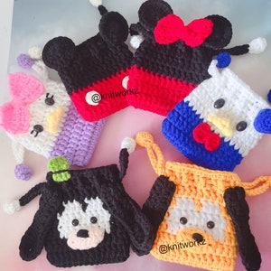 May include: Five crocheted drawstring bags with different cartoon characters. The bags are made with various colors of yarn, including red, white, blue, black, yellow, and purple. The characters include Mickey Mouse, Minnie Mouse, Hello Kitty, a dog, and a cat. The bags are all about 5 inches tall and 4 inches wide. The bags are perfect for holding small items like coins, keys, or jewelry.