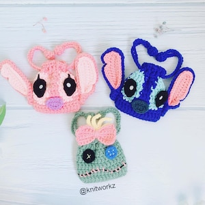 May include: Three crocheted Stitch characters from the Disney movie Lilo & Stitch. The characters are pink, blue, and green. The pink character has a purple nose and black eyes. The blue character has a blue nose and black eyes. The green character has a pink bow and a button nose. The characters are all wearing a string for hanging.