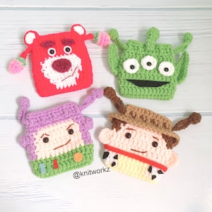 May include: Four crocheted toy character coin purses. The characters are Woody from Toy Story, Buzz Lightyear,  Alien, and  Rex. The purses are all different colours and have embroidered details. The purses are all handmade and have a unique, whimsical style.