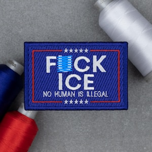 Może przedstawiać: Haftowana niebieska naszywka z białym napisem "F**k ICE" i "NO HUMAN IS ILLEGAL". Naszywka ma czerwoną obwódkę i gwiazdki. Szpule nici w kolorze czerwonym, niebieskim i białym w tle.