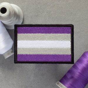 May include: An embroidered patch featuring the asexual pride flag, with purple, white and grey stripes and a black border.