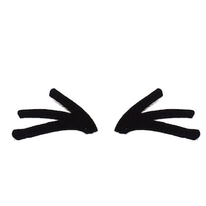 May include: Black, stylized eyelashes on a white background. The eyelashes are drawn with thick, bold lines, creating a simple yet striking graphic design. The minimalist style is suitable for various applications.