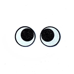 May include: Two round, cartoon-style eyes with a black pupil and a white crescent shape. The eyes have a black glittery texture and are outlined in black. The background is plain white.
