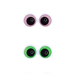 Peut inclure: Deux paires d'yeux artisanaux. La paire sup&eacute;rieure est rose avec des paillettes et des pupilles noires. La paire inf&eacute;rieure est verte avec des paillettes et des pupilles noires. Tous les yeux ont un contour blanc.