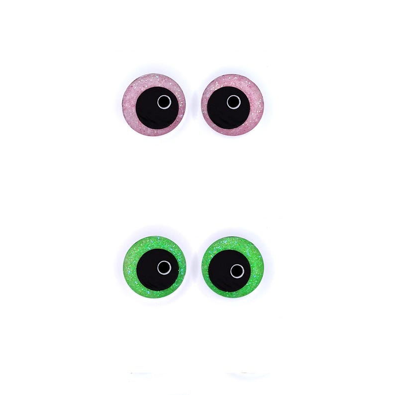 Peut inclure: Deux paires d'yeux artisanaux. La paire sup&eacute;rieure est rose avec des paillettes et des pupilles noires. La paire inf&eacute;rieure est verte avec des paillettes et des pupilles noires. Tous les yeux ont un contour blanc.