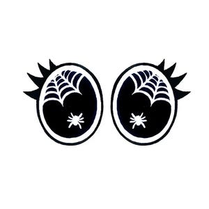 May include: Black and white Halloween-themed graphic of two cartoon eyes. Each eye features a white spider web design and a small white spider. The eyes have spiky black eyelashes.
