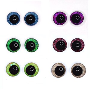 Peut inclure: Une collection de six paires d'yeux artisanaux scintillants de diff&eacute;rentes couleurs. Les yeux ont une pupille noire avec un contour blanc et sont entour&eacute;s de paillettes bleues, violettes, vertes, rouges, jaune-vert et dor&eacute;es.