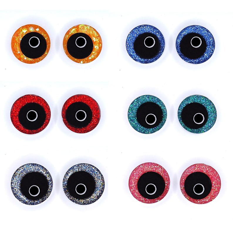 Peut inclure: Une collection de huit paires d'yeux artisanaux scintillants de diff&eacute;rentes couleurs. Les yeux ont un centre noir avec un contour blanc et sont entour&eacute;s de paillettes orange, bleu, rouge, vert, argent et rose.