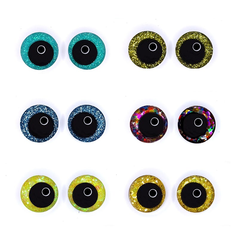 Peut inclure: Huit paires d'yeux ronds scintillants pour l'artisanat, de diff&eacute;rentes couleurs. Chaque &oelig;il a un centre noir avec un anneau blanc, entour&eacute; de paillettes dans les tons de turquoise, or, bleu, multicolore et jaune.
