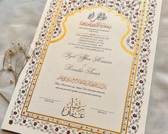 Puede incluir: Certificado de matrimonio de color marfil con borde floral dorado y burdeos. El documento incluye caligrafía árabe y texto en inglés, certificando un matrimonio. Los nombres Syed Affan Hassan y Ramsha Aamir están presentes.