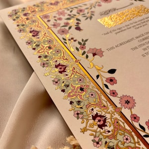 Pu&ograve; includere: Un foglio color crema con un bordo floreale dorato e rosa. Il testo "This Agreement, Made On" &egrave; stampato in inchiostro nero. Il testo &egrave; in uno stile di calligrafia islamica tradizionale.