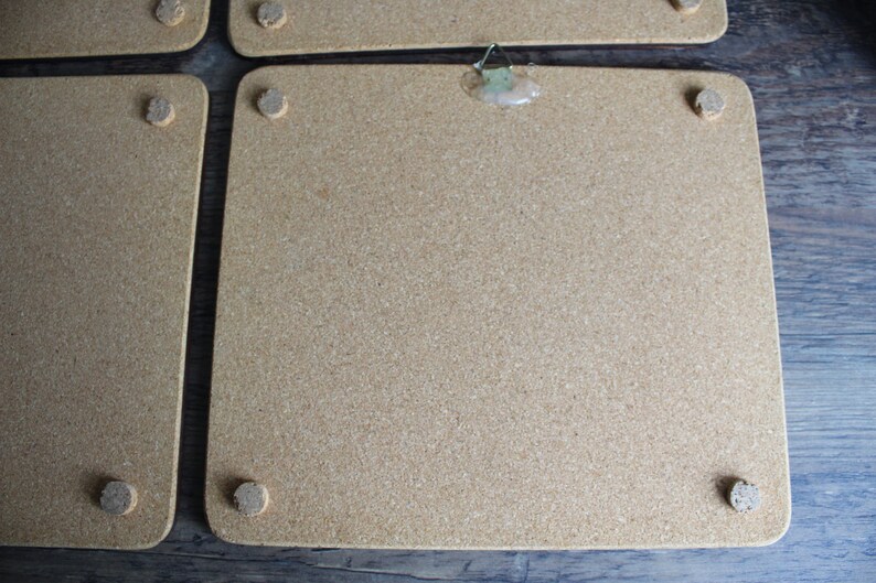 K&ouml;nnte beinhalten: Eine Sammlung rechteckiger Korktafeln mit abgerundeten Ecken. Jede Tafel hat kleine, kreisf&ouml;rmige Korkf&uuml;&szlig;e. Eine Tafel hat einen Metallb&uuml;gel, der mit Klebstoff befestigt ist.