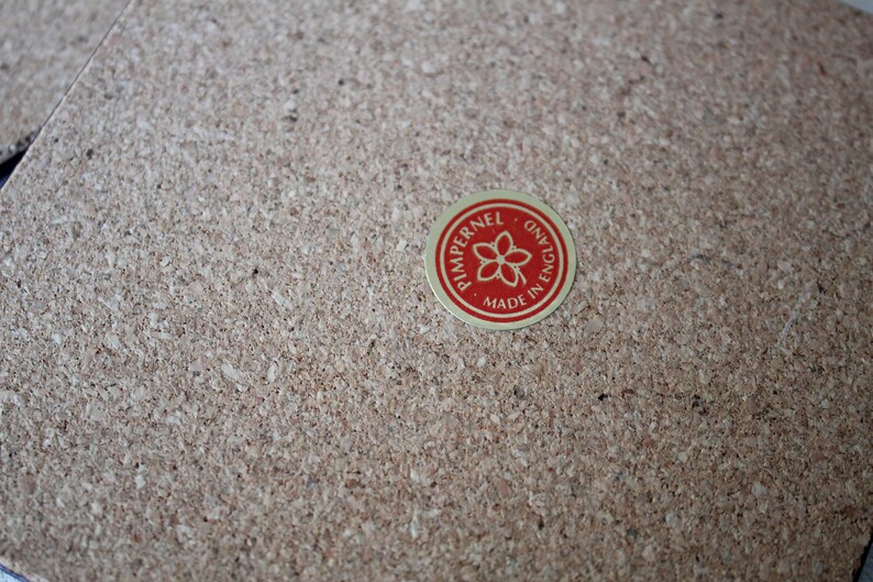 May include: A red and gold circular sticker with the text "Pimpernel, Made in England" and a flower design.