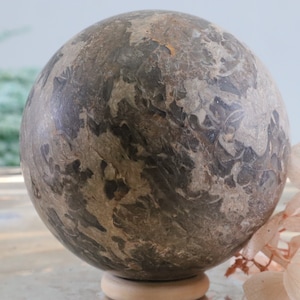 May include: A large, round, grey and brown sphere with a swirling, marbled pattern. The sphere is made of stone and has a smooth, polished surface.