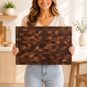 May include: A rectangular end-grain wooden cutting board with a dark brown, multi-tonal block pattern. The board features a juice groove along the perimeter and is engraved with the text "Holland" and "Est. 2026" in the bottom left corner.