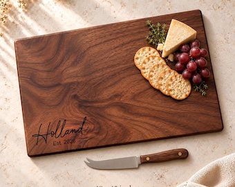 May include: A rectangular dark wood serving board measuring 10 by 15 inches, engraved with the text Holland Est. 2026. It is topped with a wedge of cheese, a cluster of red grapes, and round crackers, accompanied by a matching wood-handled knife.