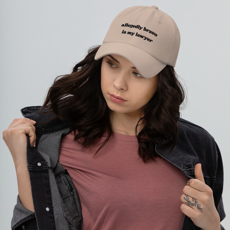 May include: A beige baseball cap with black embroidered text that reads "allegedly bravo is my lawyer".