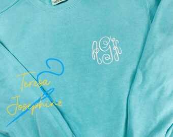 May include: A turquoise blue sweatshirt with a white embroidered monogram "AJF" on the front.