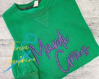 May include: Green sweatshirt with purple and blue embroidered text that reads "Mardi Gras".