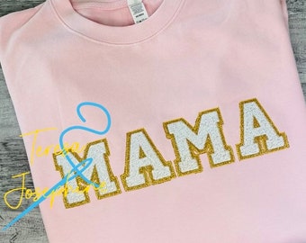 May include: Pink sweatshirt with the word "MAMA" in gold glitter letters with a white outline.