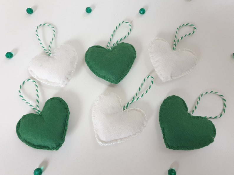 May include: Six felt heart ornaments, three green and three white, with twine hangers.