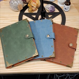 Op de afbeelding: Drie lederen dagboeken met gouden accenten en metalen studs. De dagboeken zijn groen, blauw en bruin.