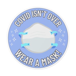 Może przedstawiać: Okrągła naklejka w kolorze niebieskim i białym z tekstem "COVID ISN'T OVER WEAR A MASK!" i białą maską na twarz z niebieskimi paskami.