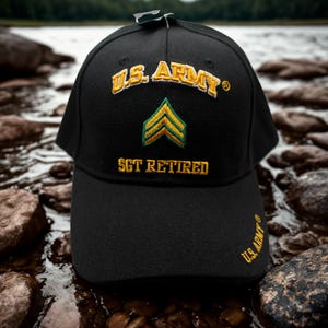 May include: Black baseball cap with embroidered text and insignia. The cap features "U.S. ARMY" in gold lettering above a green and gold chevron, with "SGT RETIRED" below. The U.S. Army logo is also embroidered on the side.