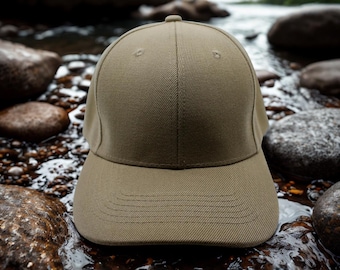 Peut inclure: Casquette de baseball kaki avec une visière incurvée. Le chapeau est fait d'un tissu texturé et comporte un bouton sur le dessus. L'arrière-plan montre un lit de rivière rocheux.