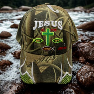 May include: A camouflage baseball cap with the text "JESUS is the WAY, TRUTH, LIFE" embroidered in white and green. The cap features a green cross and fish symbols, with a curved brim and a mesh design.