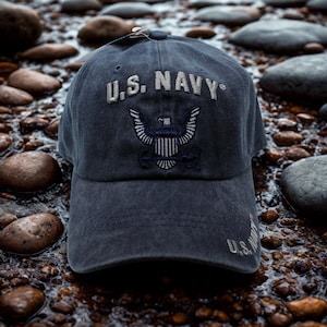 Könnte beinhalten: Marineblaue Baseballkappe mit dem Text "U.S. NAVY" in Weiß gestickt. Die Kappe hat ein marineblaues Emblem mit einem Adler- und Anker-Design. Hergestellt aus einem weichen, abgenutzten Material.