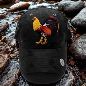 May include: Black camouflage-patterned trucker hat with an embroidered rooster design in yellow, red, and orange. The hat has a mesh back and a curved peak, suitable for outdoor wear.
