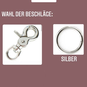 May include: Two silver metal clasps for a dog leash. The clasp on the left is a spring clasp. The clasp on the right is a simple ring. The text "SILBER" is below the ring.