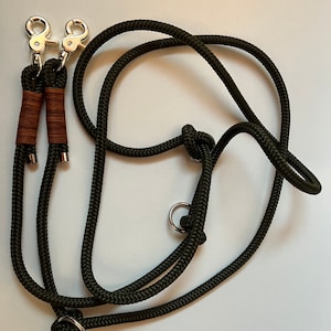 May include: A green double dog leash with two silver clips and two silver rings. The leash is made of thick rope.